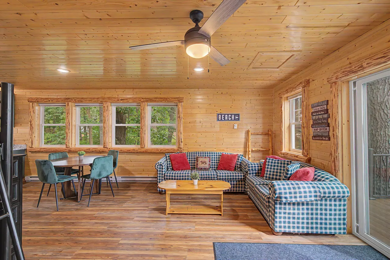 Knotty-pine bunkhouse living room with a sectional and a dining table