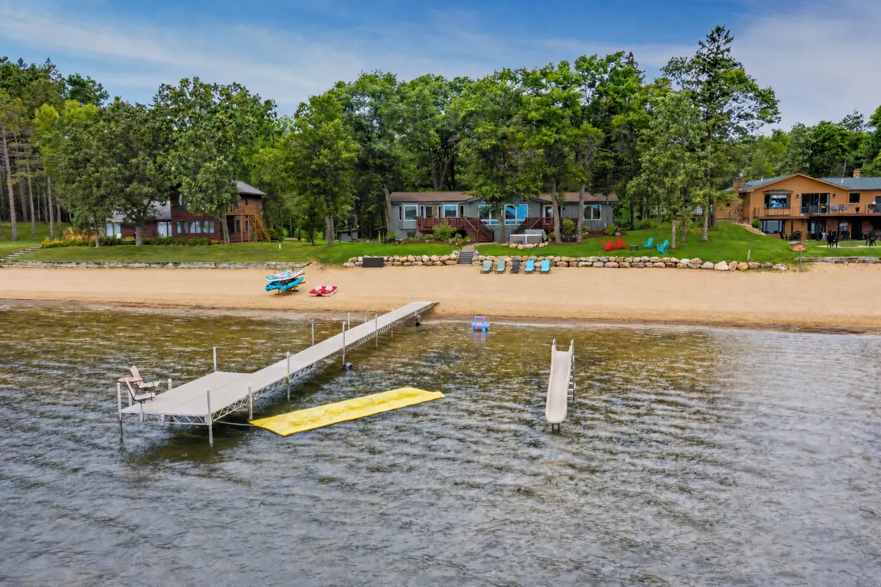 The dock and floating water mat seen from the lake, with the beach and house behind