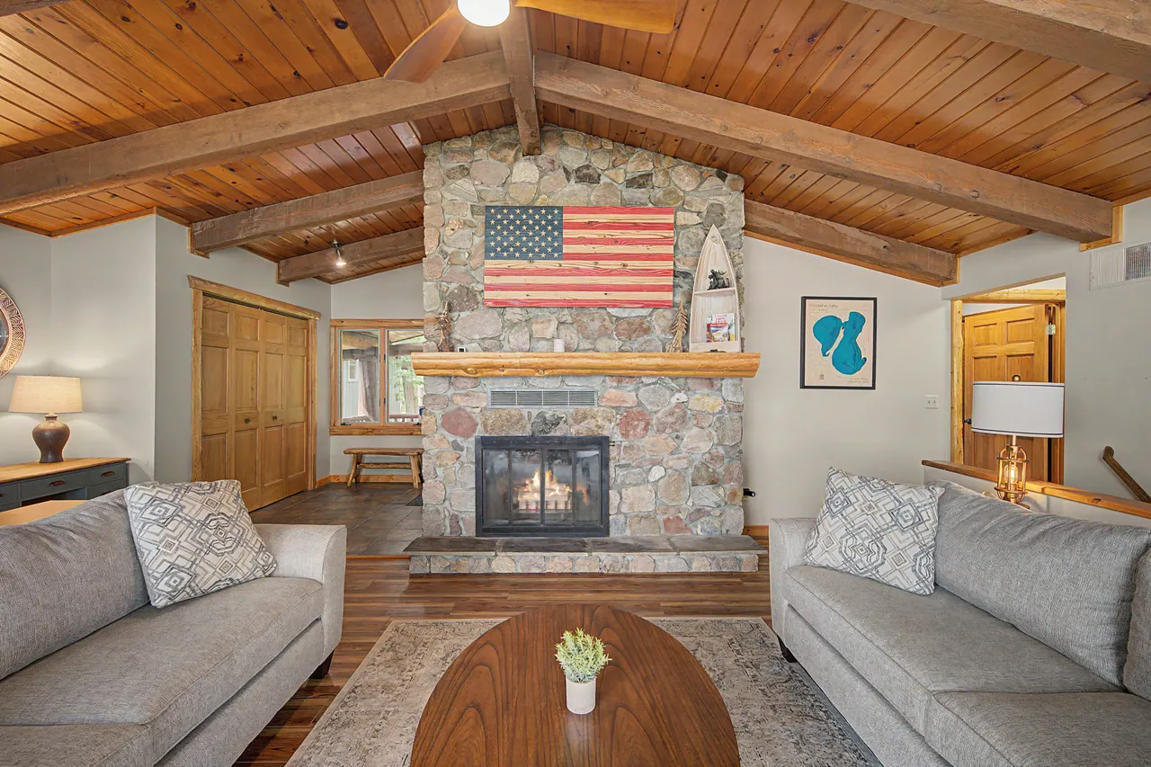 Sofas around the stone fireplace under the cedar ceiling